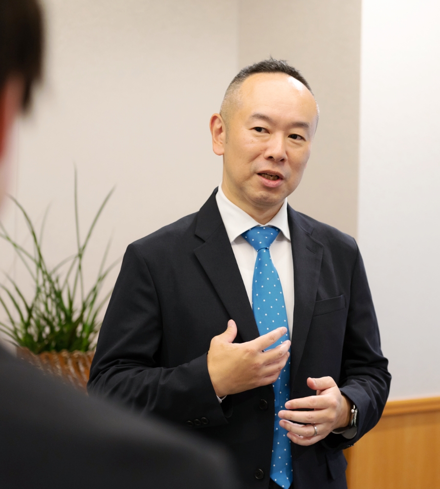システム部 部長 向田 敬博が社員と会話している風景